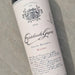 A bottle of Escribuela Garcia Malbec Grand Reserve wine resting on a textured gray concrete surface. The bottle has a dark glass body with a cream-colored label featuring elegant black script and crest details.